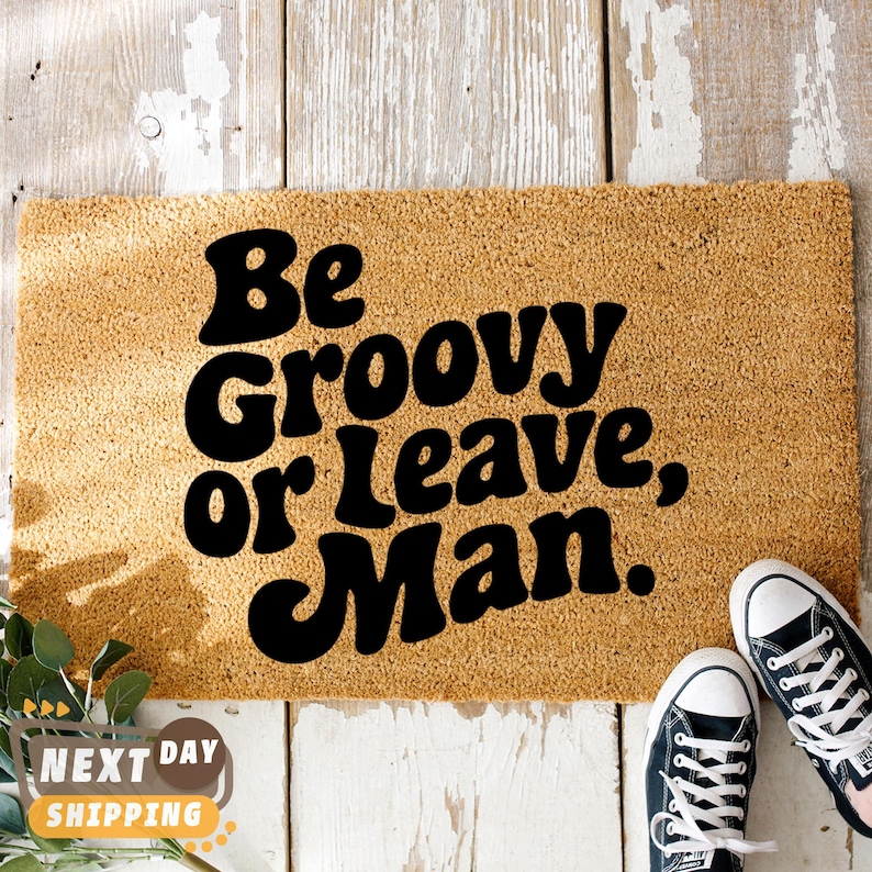 May include: A brown doormat with the text "Be Groovy or Leave, Man." in black, retro-style font.