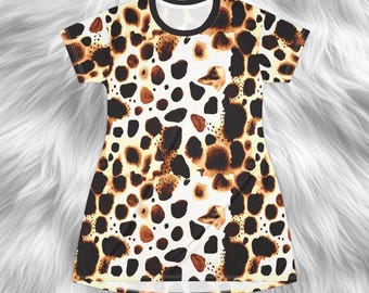 May include: A short-sleeved dress with a brown, black, and tan animal print pattern. The dress has a black neckline and a loose fit. The fabric appears to be soft and lightweight, suitable for warm weather. The dress is a casual garment.