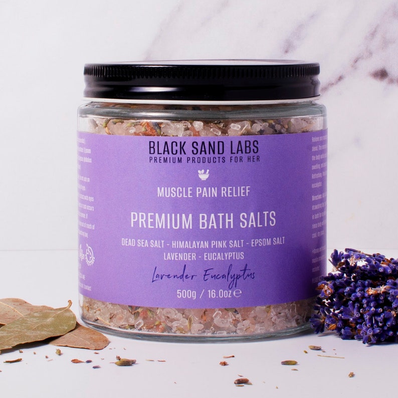 May include: A clear glass jar with a black lid containing bath salts. The purple label reads Black Sand Labs, Muscle Pain Relief, Premium Bath Salts, Dead Sea Salt, Himalayan Pink Salt, Epsom Salt, Lavender, Eucalyptus, 500g / 16.0oz.