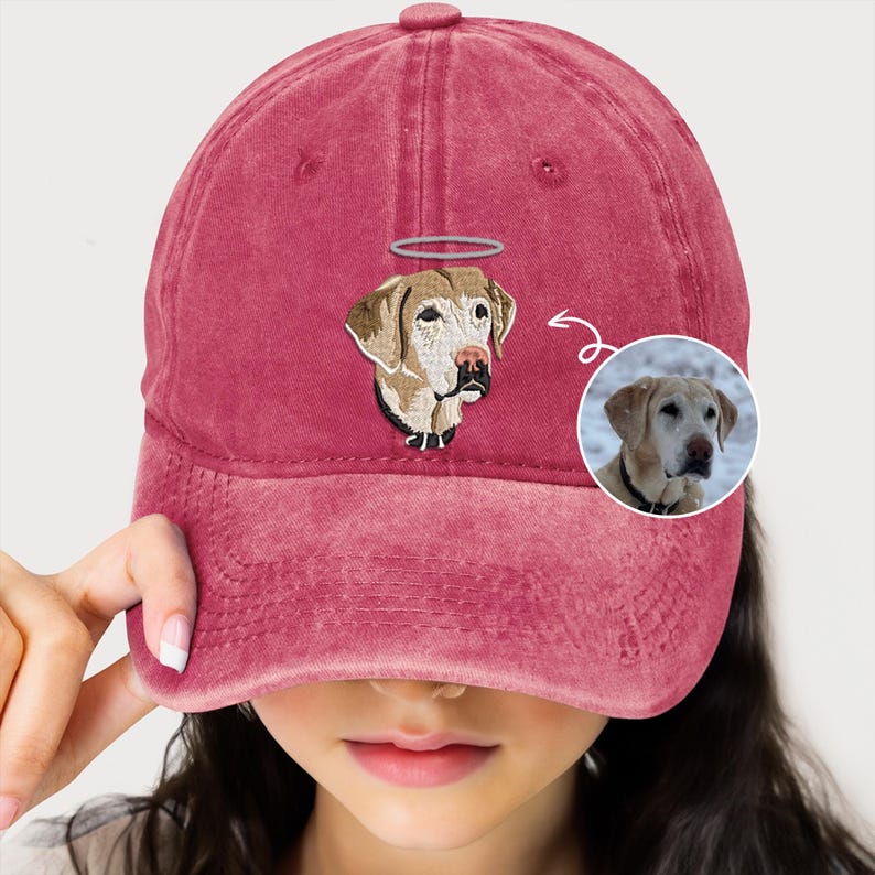 May include: A red baseball cap featuring an embroidered image of a dog with a halo. The dog is light brown with a white patch on its chest. The cap is made from a soft, comfortable material and is ideal for everyday wear.