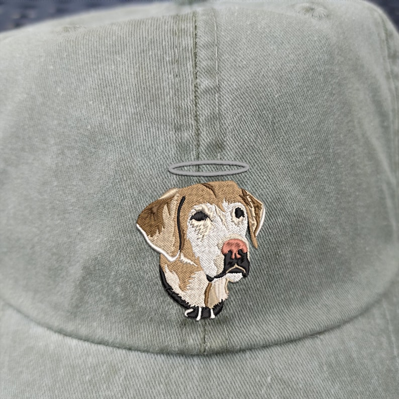 May include: A green baseball cap featuring an embroidered image of a dog with a halo. The dog is light brown with white markings and wears a black collar.