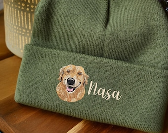 May include: Olive green knit beanie featuring an embroidered golden retriever dog and the name "Nasa" in a cursive font. The beanie has a folded brim and is made of a soft, textured material.