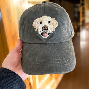 May include: A dark green baseball cap with an embroidered image of a golden retriever dog.