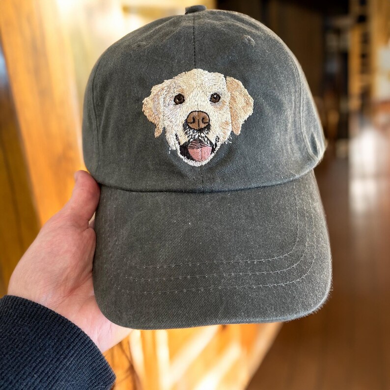 May include: A dark green baseball cap with an embroidered image of a golden retriever dog.