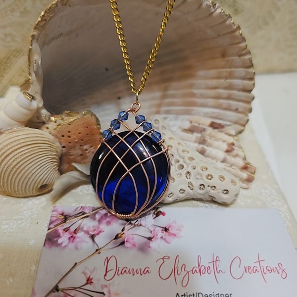 Artisan  Blue Glass, wire-wrapped in copper embelished with Austrailian crystals.  Designed by Dianna Elizabeth,  on a 18" Gold chain.