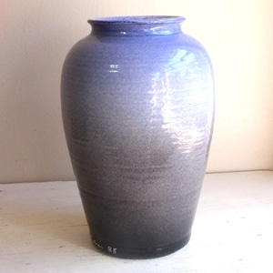 Może przedstawiać: Wysoki, ceramiczny wazon z gradientem kolorów. Wazon przechodzi od głębokiego niebieskiego u góry do ciemnoszarego u podstawy. Ma szeroki korpus i lekko rozszerzoną krawędź, odpowiedni do dekoracji wnętrz, w cm.