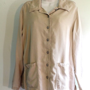 May include: A tan button-down jacket with two front pockets and a collared neckline. The long-sleeved jacket is displayed on a white mannequin and is made of a sturdy fabric. The jacket has six buttons down the front.