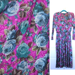Puede incluir: Un vestido largo de manga larga con fondo rosa y estampado floral con rosas azules y turquesa.