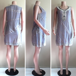 May include: A sleeveless, light blue dress with a white lace trim and beaded embellishments. The dress has a loose fit and a slightly A-line silhouette.