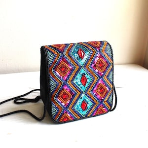 May include: A small black purse with a colorful geometric pattern of sequins and beads. The pattern features shades of blue, green, pink, orange, and red.