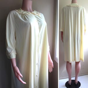 May include: A pale yellow, long-sleeved nightgown with a button-up front and a lace trim collar. The nightgown has a relaxed fit and is made of a lightweight fabric.