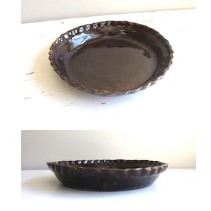 May include: A dark brown ceramic pie dish with a scalloped edge. The dish has a glossy finish and a shallow depth. The pie dish is shown from two different angles, one from above and one from the side.