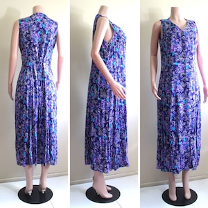 May include: A sleeveless maxi dress with a floral print in shades of purple, blue, and white. The dress has a V-neckline and a button-up front.