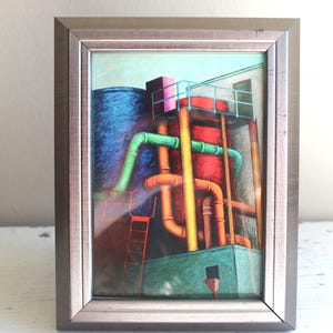May include: Framed artwork depicting an industrial scene with a blue cylindrical tank, red structures, and green and orange pipes. The artwork is in a silver-colored frame and is displayed on a white surface.