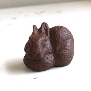 May include: A small, brown, wooden sculpture of a sleeping rabbit. The rabbit is curled up in a ball with its head resting on its paws.