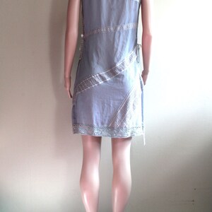 May include: A light blue sleeveless dress with a white and light brown patterned design. The dress has a lace trim at the hem and is cinched at the waist.