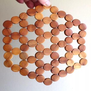 May include: A wooden coaster made of small, round, light brown pieces of wood arranged in a hexagonal pattern.