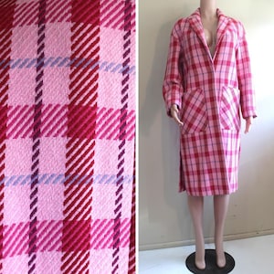 Könnte beinhalten: Ein rosa-rotes kariertes Mantel- und Rock-Set. Der Mantel hat große Taschen und einen Reverskragen. Der Stoff hat eine gewebte Textur mit einem Muster aus rosa, roten und violetten Streifen. Der Rock ist knielang.