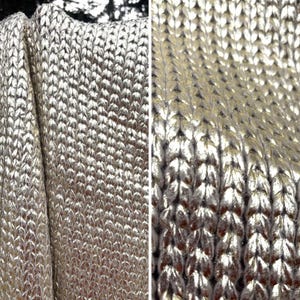 May include: A metallic gold knit fabric featuring a dense, uniform stockinette stitch pattern. The material displays a reflective, shimmering surface with a consistent texture throughout, showcasing the intricate interlocking loops of the yarn.