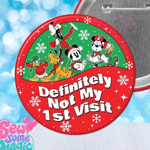 May include: A round pinback button featuring a green upper section with Disney characters including Mickey, Minnie, Donald, and Pluto in holiday attire, and a red lower section with the white text "Definitely Not My 1st Visit" and snowflakes.