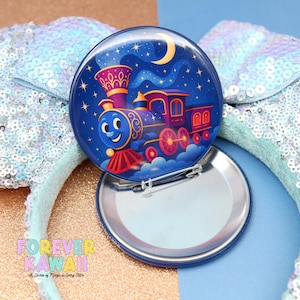 May include: A round, blue pin with a cartoon train design under a starry night sky and a crescent moon. The pin is open, revealing a silver backing and a safety pin clasp. The text "FOREVER KAWAII" is visible at the bottom.