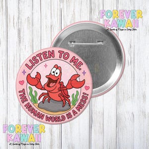 Puede incluir: Un botón rosa con una ilustración de un cangrejo de dibujos animados y el texto "LISTEN TO ME, THE HUMAN WORLD IS A MESS!". El botón tiene una parte trasera de metal y un borde rosa. Las palabras "FOREVER KAWAII" también son visibles.