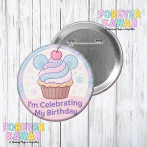 Peut inclure: Un bouton rond avec un motif de cupcake et le texte "I'm Celebrating My Birthday". Le cupcake a un glaçage bleu, rose et violet avec une cerise sur le dessus. Le bouton est argenté avec une épingle au dos. Les mots "FOREVER KAWAII" sont également sur le bouton.