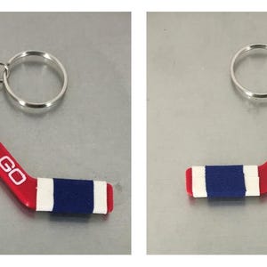 May include: Red and white hockey stick keychain with a blue stripe and the text "GO HABS GO" on one side and "CANADIENS" on the other side.