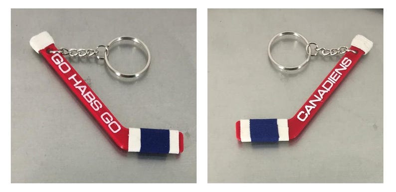 May include: Red and white hockey stick keychain with a blue stripe and the text "GO HABS GO" on one side and "CANADIENS" on the other side.