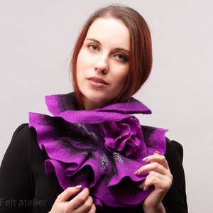 May include: A purple felted wool scarf with a ruffled design. The scarf has a large flower-shaped detail in the center.
