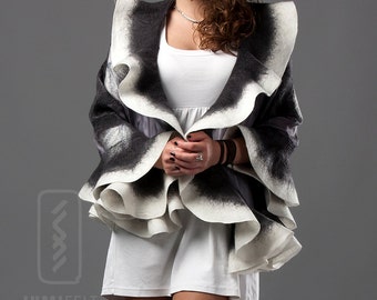 May include: A black and white felted wool shawl with ruffled edges. The shawl is draped over a person wearing a white dress.