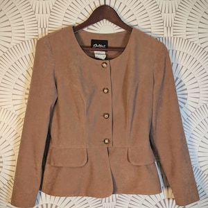 May include: A tan long-sleeved jacket with a round neckline and four gold-toned buttons down the front. The garment features two front flap pockets at the waist and a label inside the collar that reads Golbel. The jacket is displayed on a hanger.