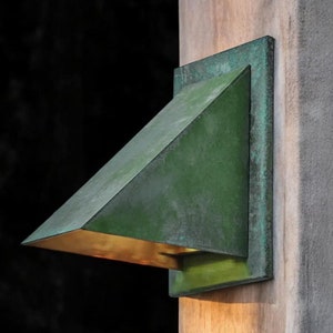 May include: A green metal outdoor light fixture with a triangular shade mounted on a wooden post.