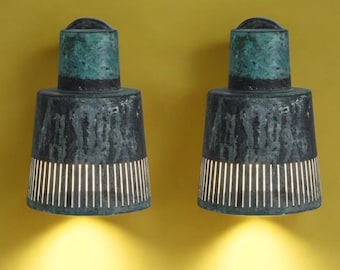 May include: Two black and green wall sconces with a light shining from each. The sconces have a textured finish and a geometric pattern.