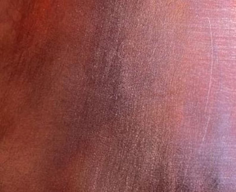 May include: Close-up of a textured, reddish-brown leather surface. The leather has a subtle sheen and a slightly grainy texture.