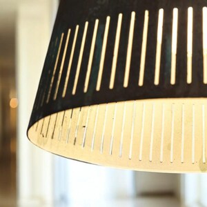 May include: A close-up of a black and white striped lampshade with a white interior. The lampshade is made of a thin, perforated material.