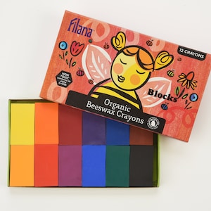 Puede incluir: Una caja de 12 crayones de cera de abeja orgánica en una variedad de colores, incluyendo amarillo, naranja, rojo, morado, azul, verde y negro. La caja presenta una abeja de dibujos animados con el texto "Organic Beeswax Crayons" y "12 Crayons".