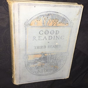 May include: A vintage book titled "Good Reading Third Reader" with a blue cover and a decorative illustration of trees and a bird.