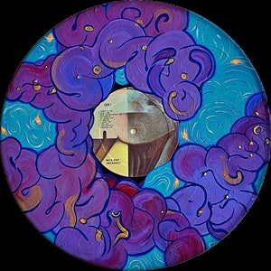 Puede incluir: Un disco de vinilo morado y azul con un diseño pintado de nubes giratorias. La etiqueta del disco es visible y dice "MCA 5507 (MCA5507)" y "Lado 1".
