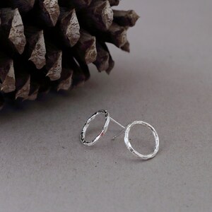 May include: A pair of silver stud earrings with a textured circular design.