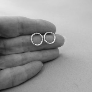 May include: A pair of small, silver hoop earrings with a textured, hammered finish.
