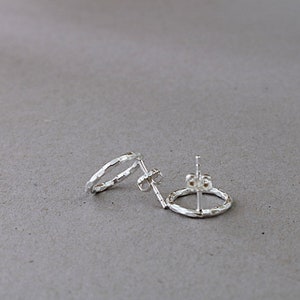 May include: A pair of silver hoop earrings with a hammered texture.