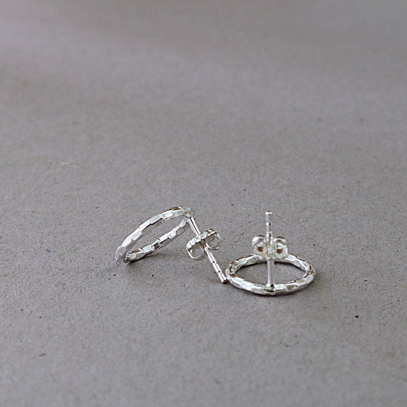 May include: A pair of silver hoop earrings with a hammered texture.