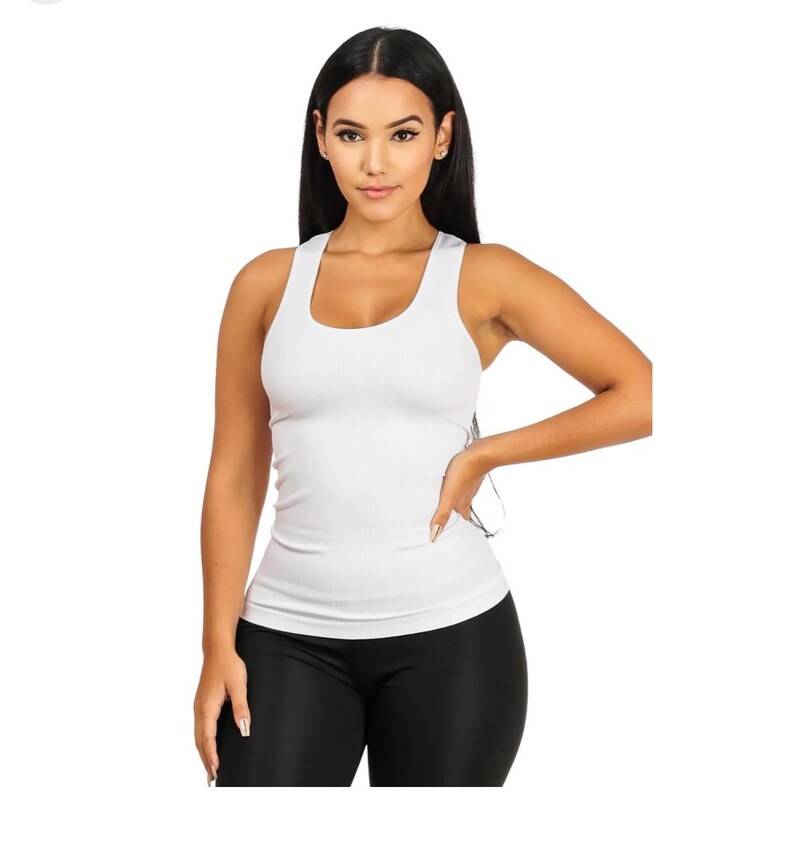 Peut inclure: Un d&eacute;bardeur blanc c&ocirc;tel&eacute; &agrave; col rond. Le d&eacute;bardeur sans manches est moulant. Le mod&egrave;le porte des leggings noirs. Le fond est blanc.