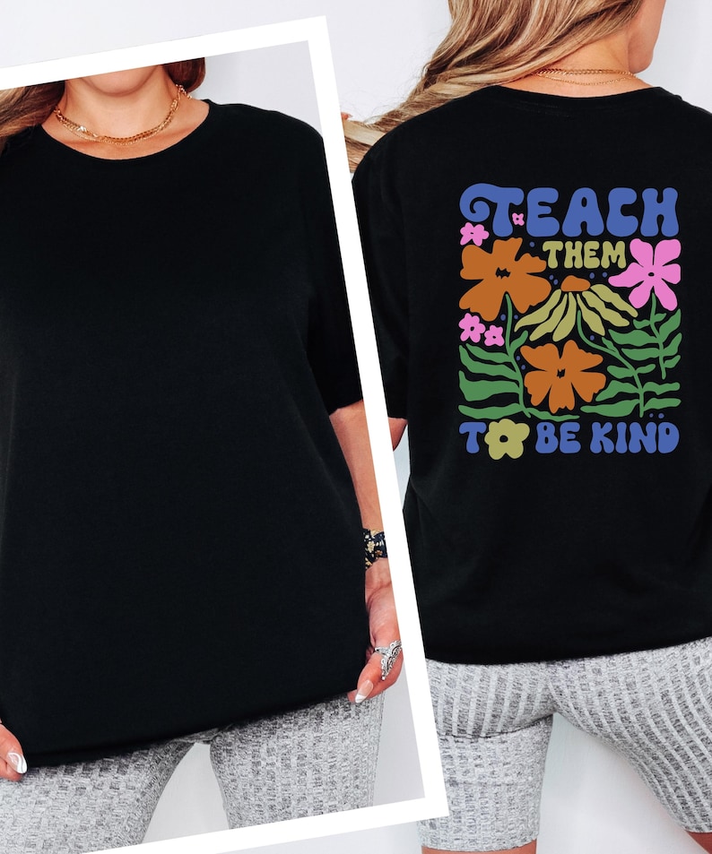 May include: Black t-shirt with the words "TEACH THEM TO BE KIND" in a colorful floral design on the back. The shirt has short sleeves and a crew neck. The front of the shirt is plain black.