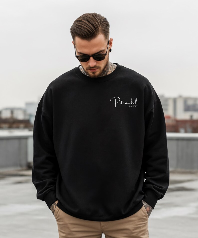 Puede incluir: Una sudadera negra de manga larga con cuello redondo que presenta el texto blanco en cursiva "Patenonkel" seguido de "Est. 2025" impreso en la parte superior izquierda del pecho. La prenda tiene un dise&ntilde;o negro liso con pu&ntilde;os y cuello acanalados.