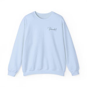 Puede incluir: Una sudadera de color azul claro con cuello redondo, mangas largas y pu&ntilde;os, cuello y dobladillo acanalados. En la parte superior izquierda del pecho, el texto "Patenonkel" est&aacute; impreso en una elegante fuente cursiva, con "Est. 2024" debajo.