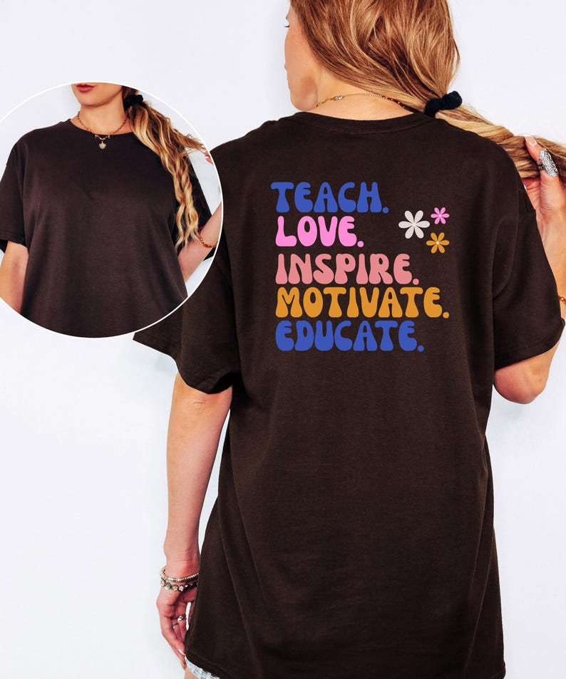 May include: A dark brown t-shirt with the words "TEACH. LOVE. INSPIRE. MOTIVATE. EDUCATE." in colorful text on the back. Two small flower graphics are also present. The shirt has short sleeves and a round neckline.