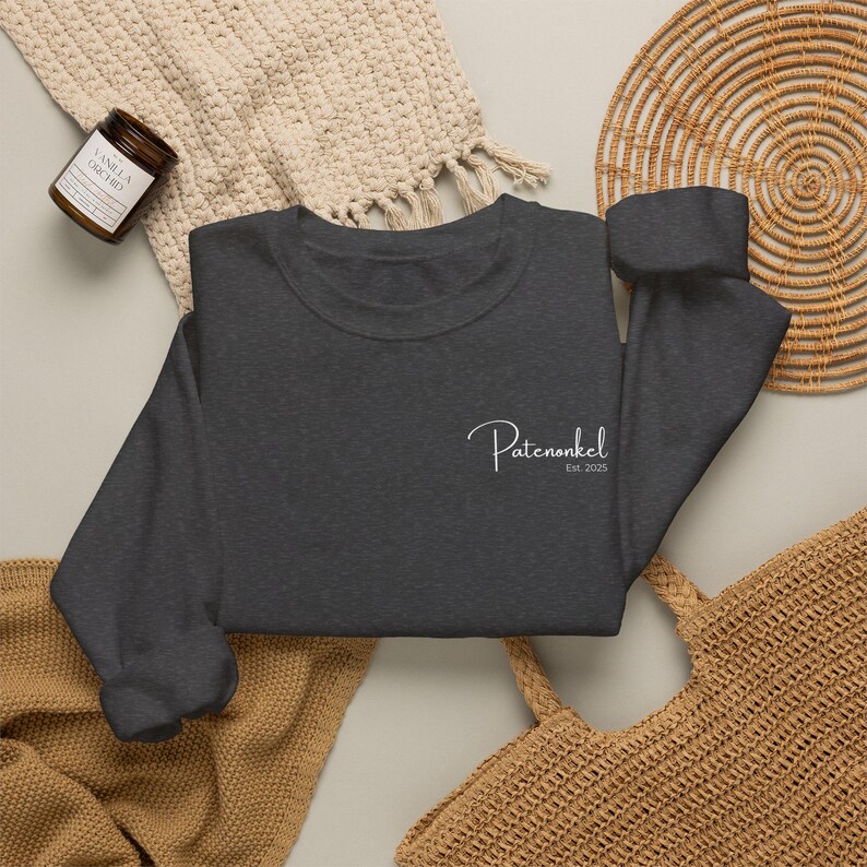 Puede incluir: Una sudadera de cuello redondo en color gris carb&oacute;n oscuro con texto blanco en cursiva en el pecho izquierdo que dice Patenonkel Est. 2025. La prenda tiene mangas largas con pu&ntilde;os acanalados y un cuello tambi&eacute;n acanalado.