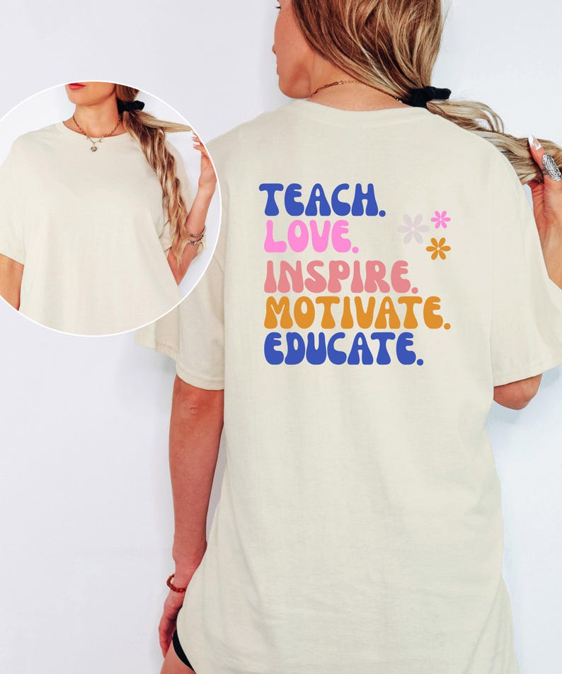 May include: Cream-colored t-shirt with the words "TEACH. LOVE. INSPIRE. MOTIVATE. EDUCATE." in blue, pink, orange, and blue lettering. Two small flower graphics are also present. The shirt is a casual style.